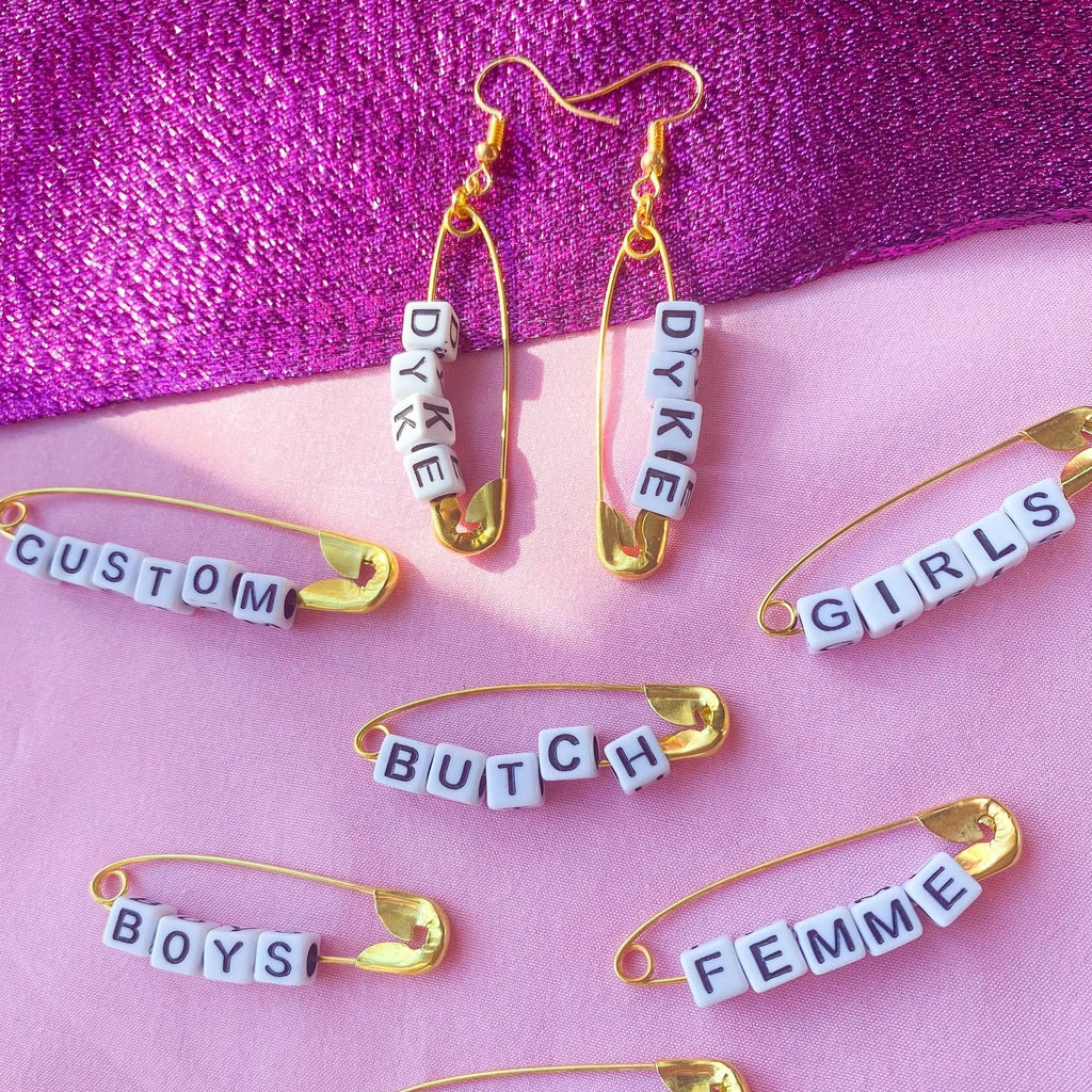 Gold safety pin word earrings Leftbians