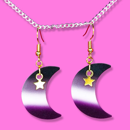 Shrinky dink earrings in the shape of a crescent moon. The colour of the charm is the asexual pride flag with a small gold star charm hanging at the top.