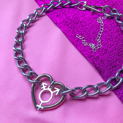 Chunky chain necklace with a love heart O ring in the middle, with a transgender symbol charm attached.